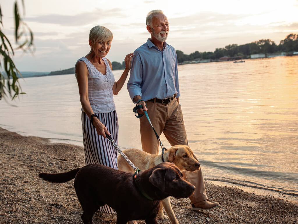 Buffalo – Illinois Seniors (1) A senior couple walking with their dog by the lake at sunset in Illinois.